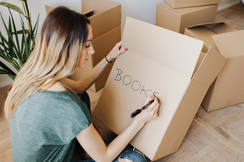 Woman writing books on moving box