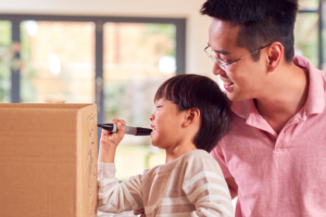 dad and son writing on cardboard box